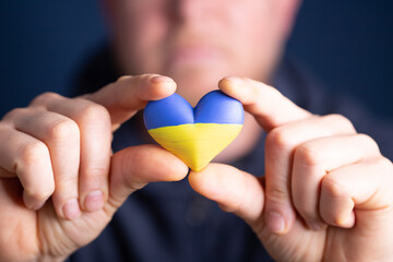 Heart flag of Ukraine in human hands. No war, peace for Ukraine concept.