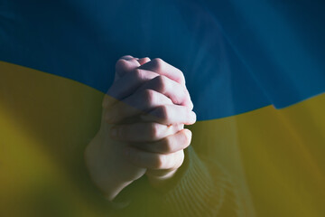 Close-up on ukrain flag with praying hands