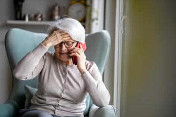 Senior woman feeling pain while consulting doctor on her smart phone
