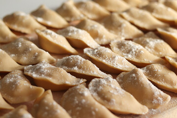 Homemade vareniki or dumplings, filled with mashed potato on wooden table. Cooking raw dumplings with potatoes. Top view, rural style. Ukrainian national dish.