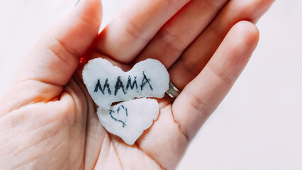 Word Mama written on broken handmade heart in a hand. 