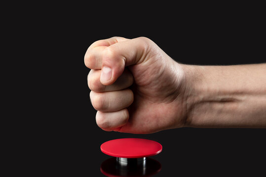 A man's hand presses a big red button. Red button on a dark background. The threat of using nuclear or chemical weapons of mass destruction. Rocket launch at the push of a button