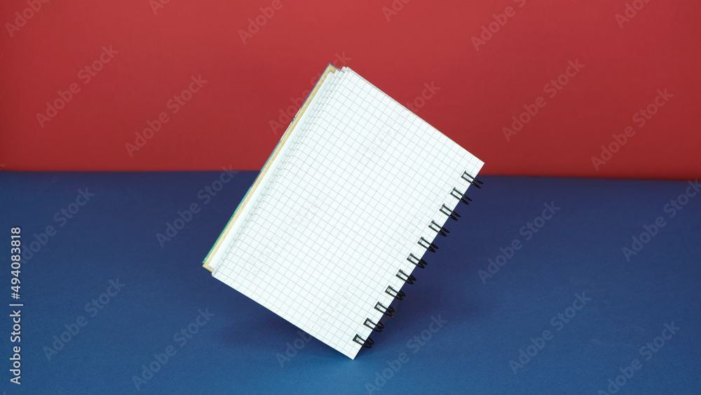 Poster open notebook with a blank page in a cage with the blue and red background