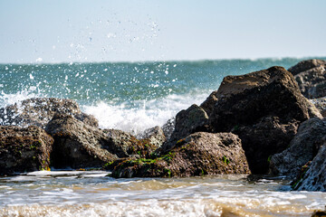 Fototapeta na wymiar Waves crashing over rock groynes at low tide