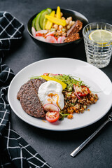 Bowl with quinoa, vegetable meat, patzot egg. avocado, carrot, cucumber, cherry tomato, pickled corn, radish, microgreen on a dark concrete table. Copy space