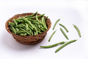 Fine green beans in a wicker bread basket on white background