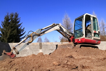 Minikoparka na placu budowy. Mini excavator at the construction site.