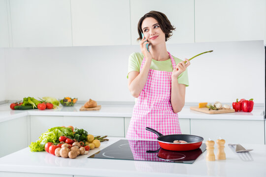Photo of charming positive person speak telephone frying salmon enjoy morning kitchen indoors