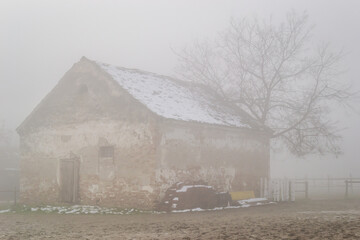 Old farmhouse covered in thick fog during the day