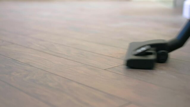 vacuum cleaner close cleaning dirty floor. A woman with a vacuum cleaner cleans the parquet at home.