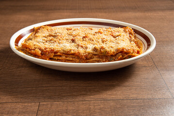 Vegan food, Lazanha de chimeji, in a clear bowl on wooden surface, selective focus.