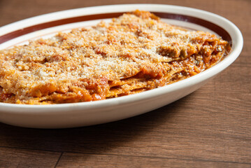 Vegan food, Lazanha de chimeji, in a clear bowl on wooden surface, selective focus.