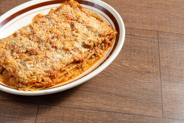 Vegan food, Lazanha de chimeji, in a clear bowl on wooden surface, selective focus.