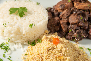Vegan food, vegan feijoada, rice and farofa on a white plate, over wood, selective focus.
