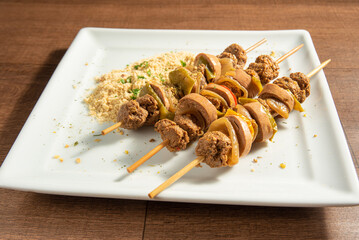 Vegan food, vegan skewers with farofa on a white plate, over wood, selective focus.
