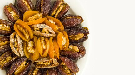 Walnuts are wrapped in dates and dried apricot fruits,designed in plate on white surface with copy space.Ramadan Concept