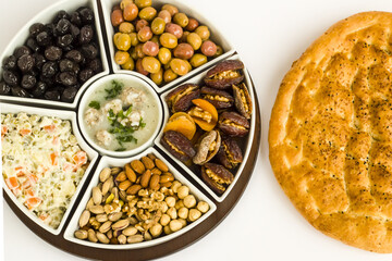 Traditional Ramadan iftar menu set with soup,olives,date fruit,nuts and circular Ramadan Bread.Top view
