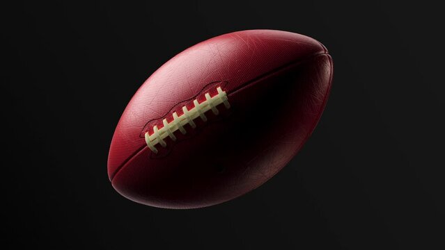 An American football ball, isolated on a black background, slowly revolves around itself. 3D photorealistic animation, 4K alpha channel, motion graphics.