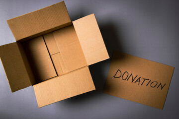 Empty open cardboard box and card with inscription Donation on gray background. Top view