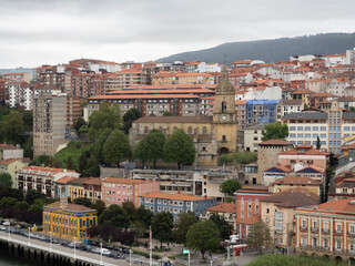 Fototapeta na wymiar Vistas de la ciudad de Bilbao, junto al mar, con montaña al fondo y cielo nuboso en verano 2020