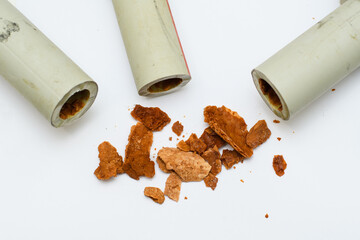 A pile of brown debris (lime, rust and scale) from old polypropylene water pipes on a white...