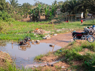 two diesel generators standing in a big puddle of water at a bike washing station in liberia