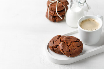 Chocolate cookies for breakfast with a cup of coffee with milk in bottle on a white table