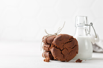 Stuck of chocolate brownie cookies on white background and milk in glass bottle. Homemade.