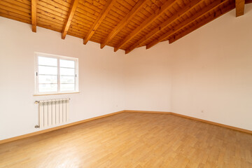 Empty room with wooden floating laminate flooring. House interior, wide bedroom space. Newly recently painted new apartment or house. Wood floor and ceiling. Real state and property management