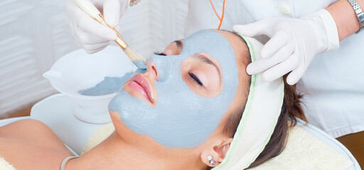 Young woman with facial mask lying in beauty health spa center and getting beauty skin treatment