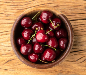 Red cherries on a bowl over wooden table