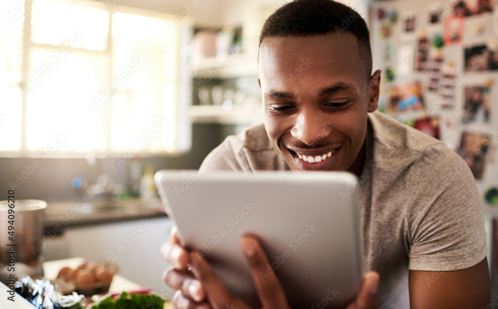 Canvas Prints I should definitely try this recipe out. Cropped shot of a handsome young man using a digital tablet while making breakfast in his kitchen at home.