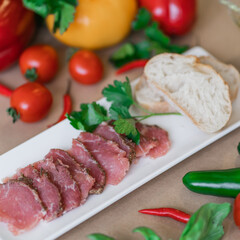 salted meat on a plate with basil and tomatoes