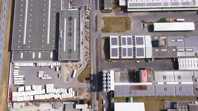 Aerial view moving over comapny buildings with flat roofs and photovoltaics on their roof.