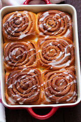 Traditional cinnamon buns with icing on a wooden table. Rustic style.