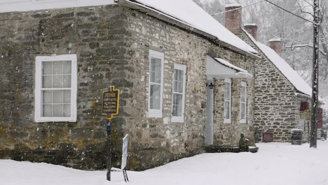 Snowfall in front of old stone buildings on historic Huguenot Street