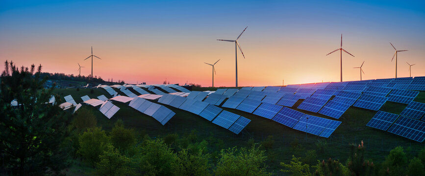 panoramic view of photovoltaic panels and wind turbines in the light of the rising sun, clean energy concept