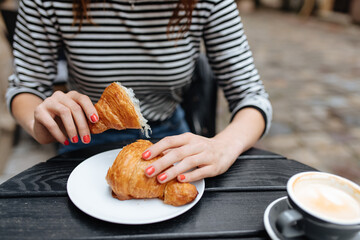Close up of woman sitting at cafe with croissant and coffee