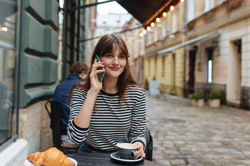 Fototapeta premium Pleasant woman having mobile talk on cafe terrace