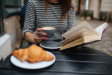 Close up of woman enjoying coffee at cafe with book in hands