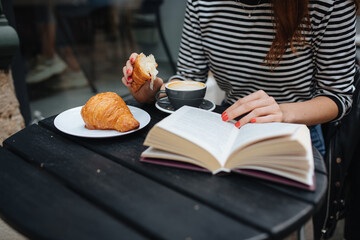 Woman reading book and drinking coffee on cafe terrace