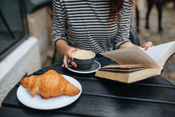 Close up of woman reading book and drinking coffee at cafe