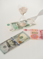 Rubles, dollars, yuans and hourglass on the white background. Time is money concept