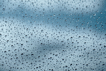 Rain drops on window with clouds in background