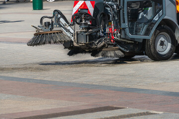 Municipal road and sidewalk cleaning machine on the city streets works on the square on a sunny day