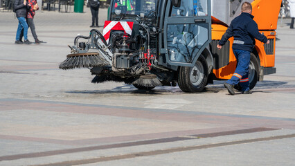 The machine cleans the city square. The driver of a communal vehicle for cleaning roads and...