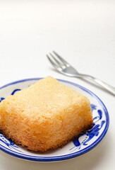 Traditional Colombian dessert, called Enyucado, made of cassava as a base ingredient and pieces of coconut and grated cheese,soft and crunchy texture, cooked in the oven.Background white. Closeup.