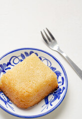 Traditional Colombian dessert, called Enyucado, made of cassava as a base ingredient and pieces of coconut and grated cheese,soft and crunchy texture, cooked in the oven.Background white. Closeup.