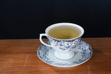 cup with lemongrass green tea, fine herbs cinnamon old crockery in the background