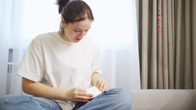 a young woman sits on the couch and makes a package for baking. boxes for bakery